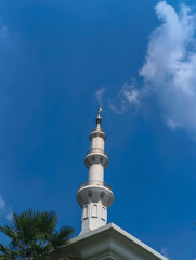 Obraz premium White Mosque Minaret Against a Bright Blue Sky with Clouds