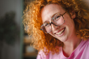 Fototapeta na wymiar Happy red-haired young woman smiling with freckles wearing glasses