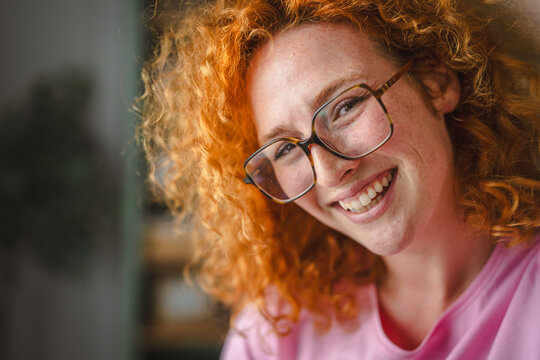 Happy red-haired young woman smiling with freckles wearing glasses