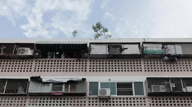 Residential apartment building in Din Daeng district, Bangkok, Thailand. Urban daytime apartment facade texture with small trees on the roof.