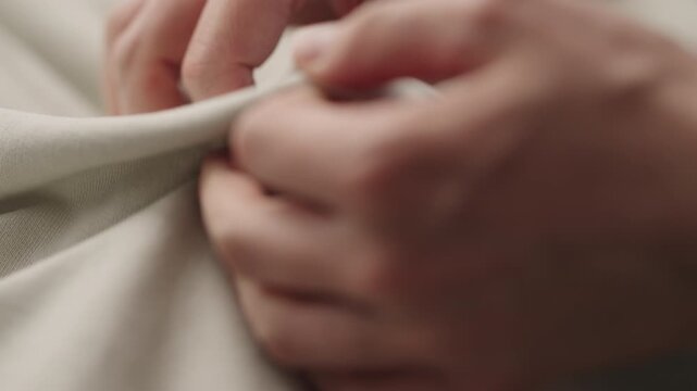 man manually check ivory color cotton fabric for clothing with hands