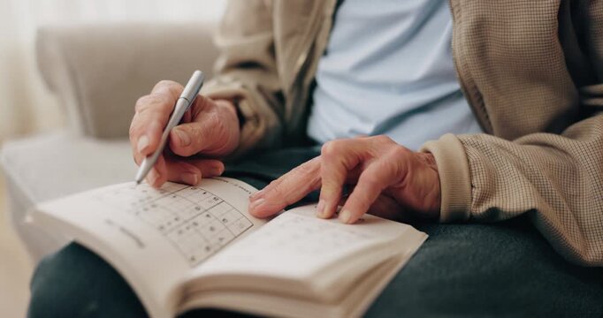 Senior, hands and writing with sudoku in home for fun activity, game or puzzle on sofa. Elderly, male person or number with book or blocks for cognitive problem solving, memory or concentration