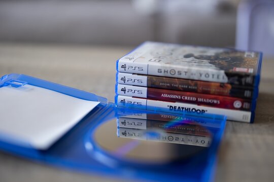 BRECHT, BELGIUM &ndash; July 10, 2026: Stack of PlayStation 5 game cases beside an open empty PS5 game box, showcasing physical video game media and console gaming.
