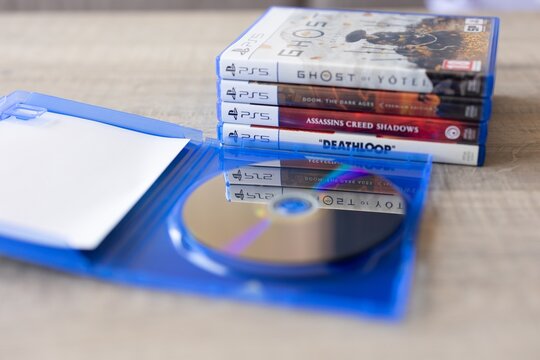 BRECHT, BELGIUM &ndash; July 10, 2026: Macro photo of PS5 game boxes stacked with an open empty game case in the foreground, highlighting physical gaming media.