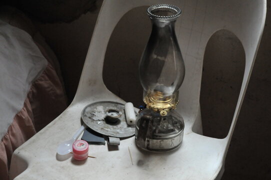 a kerosene/paraffin lamp and a candle on a chair