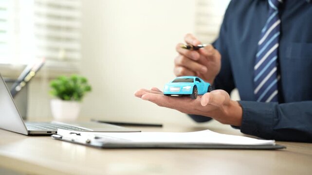 Insurance agent presenting a car model over policy documents, symbolizing auto insurance, vehicle protection, and financial security.