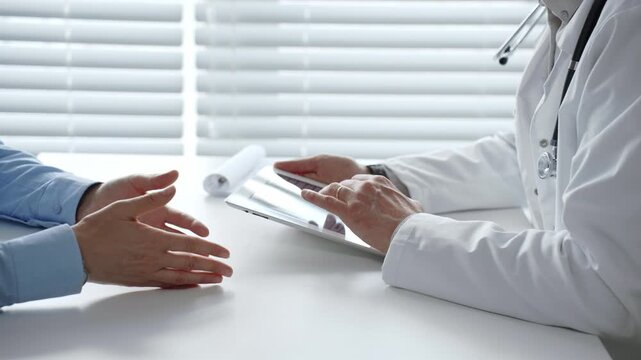 Doctor reviews digital health records with patient on tablet, explaining diagnosis and treatment options to support informed decisions and clear communication in a modern clinic setting