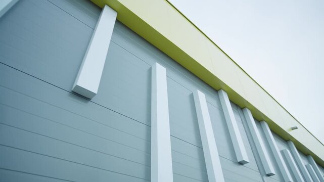 Modern facade shows sleek panels with white accent bars under gloomy sky. Clean design creates professional and stylish impression
