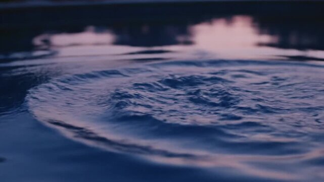 Symmetrical water crown splash on still liquid surface during blue hour with violet sunset reflections and dark tree silhouettes in background, macro impact photography.