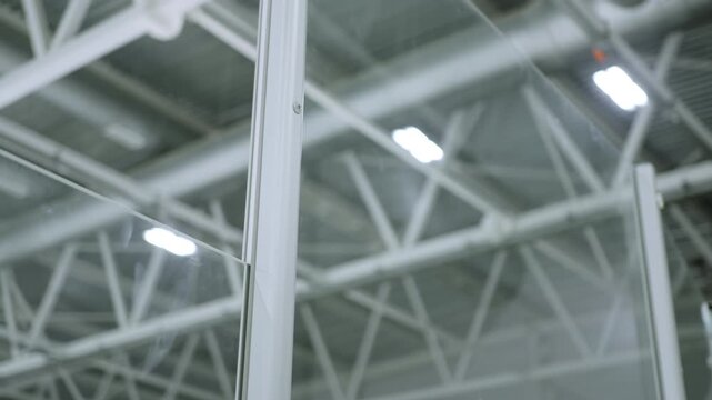Protective glass panels feature metal frames under industrial roof. Safety barriers create organized secure environment inside sports arena