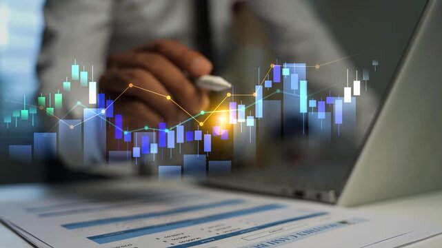 Business person using a laptop with glowing holographic stock market charts over financial reports, Business trading data analysis investment growth and modern office work