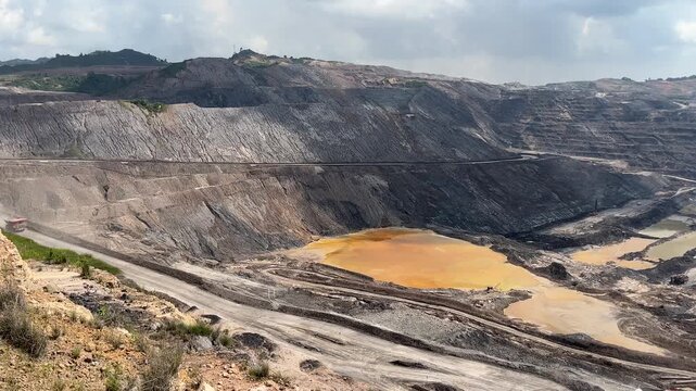 Wide View of Terraced Open Pit Mine Pit with Sediment Pond and Heavy Machinery
