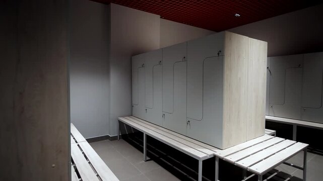 Lockers with light wood and grey panels configured in private changing area. Distinctive design features curved doors with secure locks
