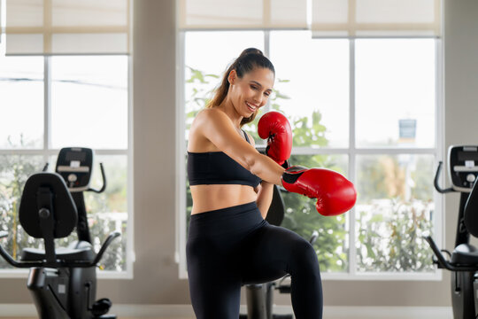 Confident young woman in red boxing gloves enjoying boxing training and footwork in the gym. Scene for personal coaching, weight loss journey, daily workout motivation and strong body.