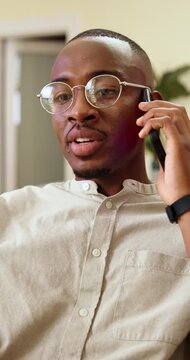 Phone call, discussion and happy man with glasses in business, headhunter and chatting with contact. Recruiter, smile and black person with mobile, communication and planning for interview in office