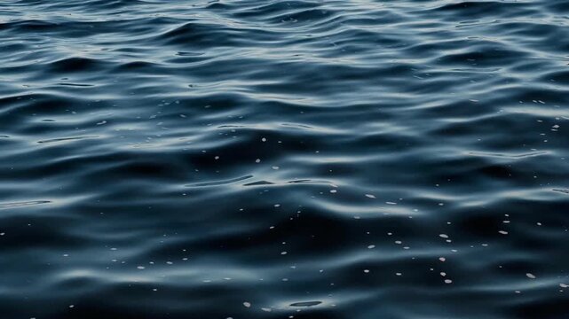 Close up shot of peaceful deep blue sea surface rippling under soft daylight. Minimalist natural liquid background, abstract water movement, tranquility concept.