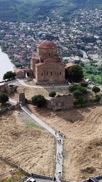 Aerial view of jvari monastery, a historic landmark in mtskheta, georgia, overlooking the confluence of the mtkvari and aragvi rivers, with tourists visiting the site