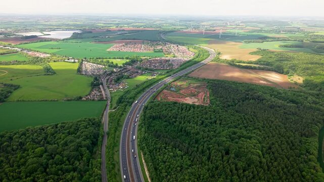 Aerial landscape footage  of a major motorway in the UK winding its way through countryside into the distance with traffic and copy space