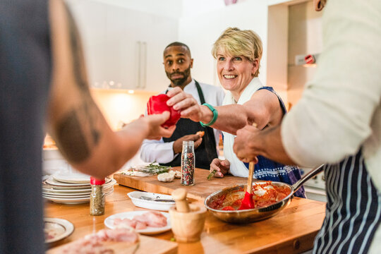 Group cooking together, sharing ingredients in a lively kitchen scene.