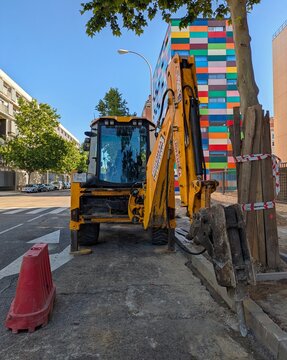 Maquinaria industrial. Vista de frente de una retroexcavadora color naranja con brazo con martillo hidr&aacute;ulico aparcada en Madrid, Espa&ntilde;a, 14 de mayo de 2026