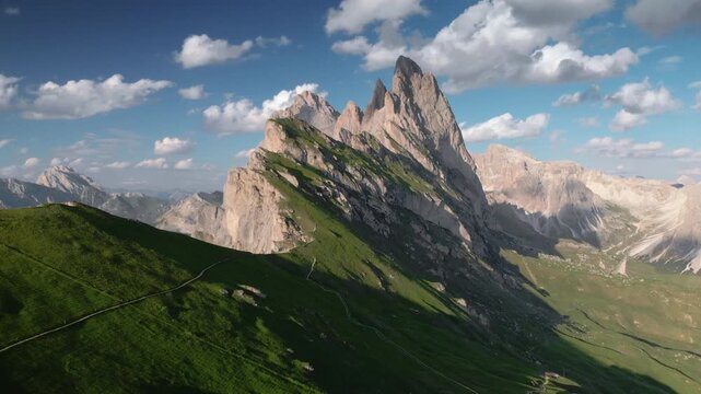 Aerial view of rugged Dolomites mountain peaks at famous Seceda mountain range against blue sky with clouds in summer