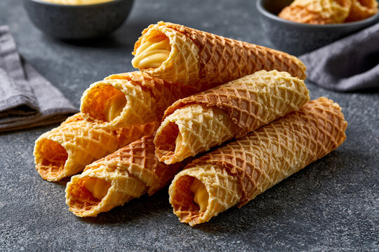 Crispy rolled wafers on a dark table setting
