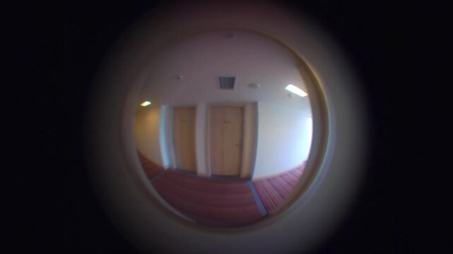 Fish-eye view of a hallway seen through a door peephole in 4k slow motion 60fps