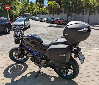 Vista lateral de moto Suzuki SV650 Naked con maletas SHAD SH23 y ba&uacute;l trasero SHAD SH39, estacionada en Madrid, Espa&ntilde;a, 14 de mayo de 2026