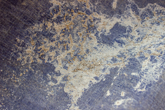 Texture of dark blue woven plastic tarpaulin dirty with dry white cement stains and coarse sand.
