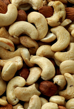Almond and cashew nuts in big pile on table close up. Large amount of brown nuts
