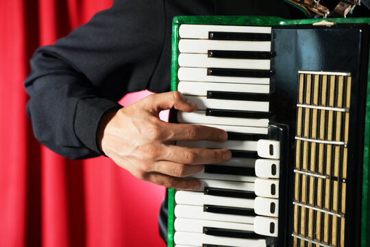 Man playing piano accordion on stage, closeup