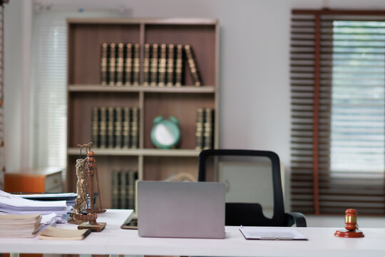 Lady Justice statue with laptop and legal documents on a lawyer's desk, representing law, justice, compliance, and legal services in a professional office setting