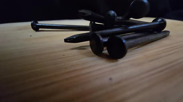 Close-up of black iron nails arranged on a clean wooden surface. High-quality macro shot showcasing construction materials and hardware tools for DIY, carpentry, or industrial renovation projects.