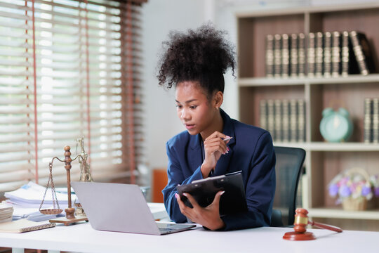 Female lawyer focusing on legal work, researching regulations, and preparing documents in her modern office, offering justice and expert legal advice