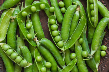 Freshly harvested green pea pods filled with sweet peas, captured in a detailed close-up that celebrates seasonal farming and healthy eating. © Tanya