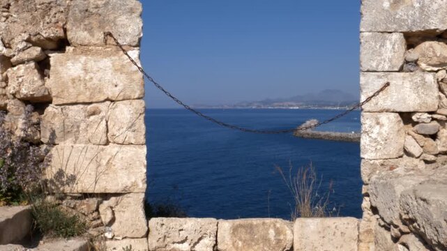 Panoramic Mediterranean sea view through ancient stone embrasure at Fortezza of Rethymno, Crete
