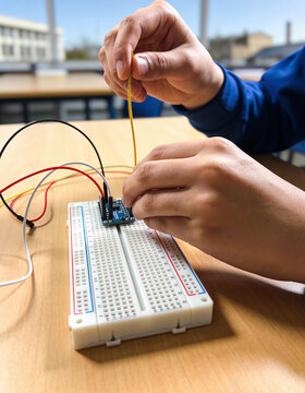 Hands placing electronic component on breadboard circuit