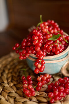 Fresh red currants in a bowl on a woven surface ready for cooking or baking during a warm afternoon