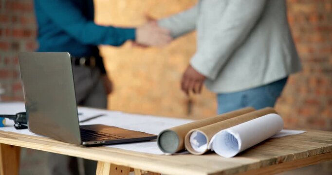 Blueprint, building and laptop with businesspeople shaking hands on construction site for agreement. Computer, deal and handshake architect team on worksite for greeting, partnership or thank you