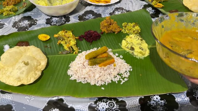 Traditional Onam sadhya rice Sambar, Rasam, parippu dal curry ghee Pappadom Payasam on banana leaf Onam Vishu Pongal Diwali festival vegetarian food Kerala Tamil Nadu South India. 4k video footage