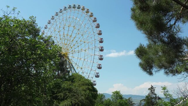 Theme par kin Georgia. Big ferris wheel against blue sky and mountains.