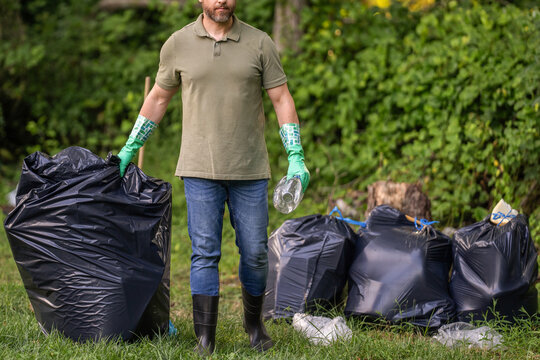 Keeping garbage in black bag for trash. Pollution and recycling. Man cleaning up park. Outdoor cleanup activity. Environmental protection. Picking up garbage plastic for cleaning