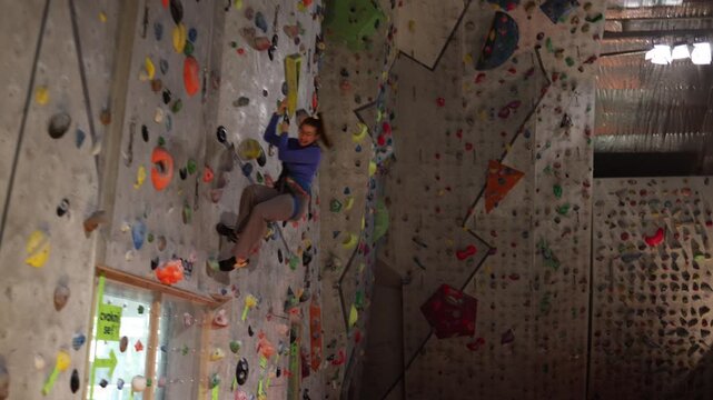 Overcoming fear of descent climber hesitates then pushes off wall and lowers on safety rope showing courage controlled movement and emotional tension