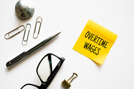 Overtime Wages yellow sticky note with glasses pen and office supplies on white background, labor law and employment concept