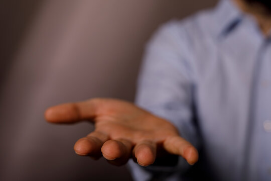 A man in a blue shirt offers an open hand for help or to receive