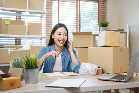 Young Asian woman owner of small online store packing customer orders in the home office.