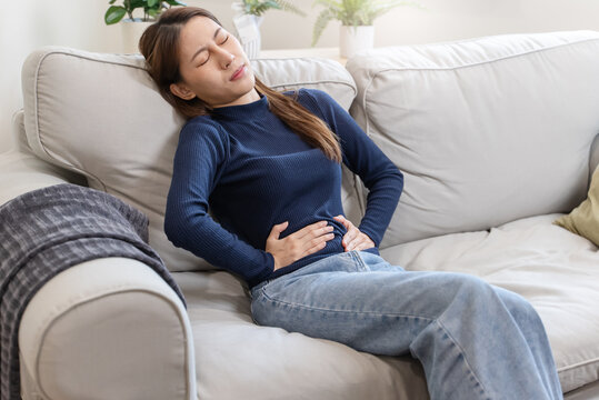 young woman gripping her stomach have abdominal pain .