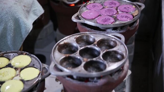 Colorful Indonesian mini pancakes cooking in traditional molds over charcoal, authentic street food preparation, close-up culinary footage.