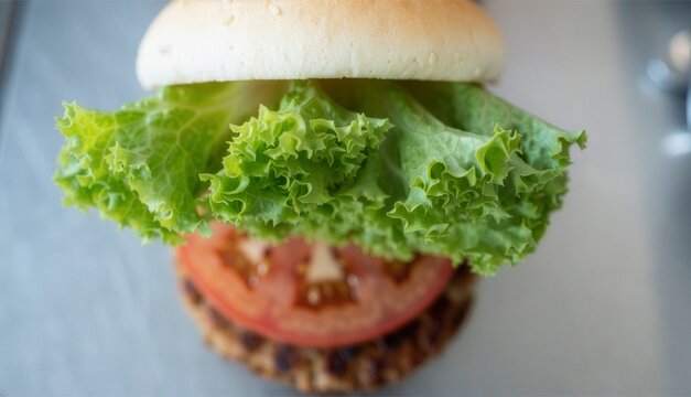 Top-down macro shot focusing on the crisp green frilly lettuce layer inside a gourmet burger with blurred tomato and patty below, ultra-shallow depth of field, commercial food photography.