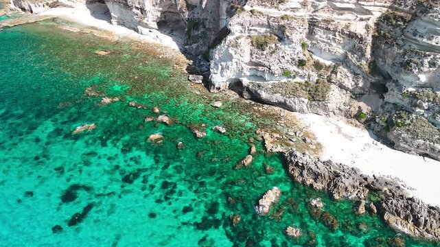 Breathtaking aerial view of Spiaggia di Riaci, one of Calabria's most pristine beaches, showcasing its dramatic rocky promontory